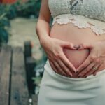 Pregnant Woman Wearing White Skirt Holding Her Tummy